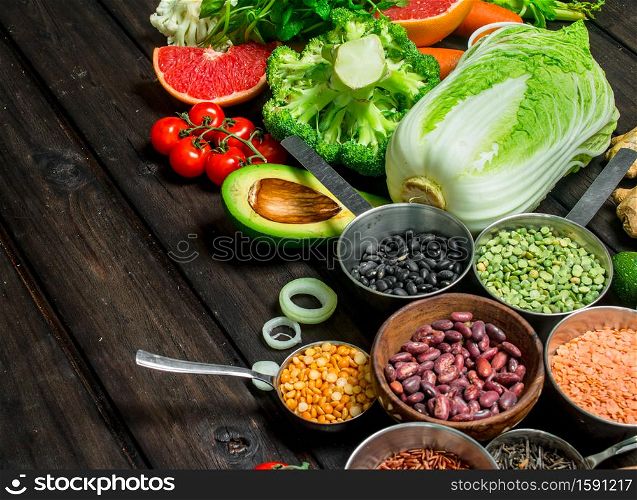 Healthy food. Assortment of cereals with legumes and organic vegetables. On a wooden background.. Healthy food. Assortment of cereals with legumes and organic vegetables.