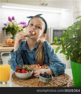 Healthy food at home. Cute little girl eats fruit salad 