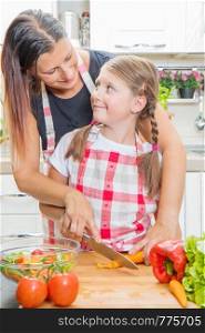 Healthy food at home. Happy family in the kitchen. Mother and child daughter are preparing the vegetables