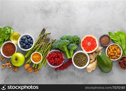 Healthy food background, spinach, quinoa, apple, blueberry, asparagus, turmeric, red currant, broccoli, mung bean, walnuts, grapefruit, ginger, avocado, almond, green peas and goji, top view