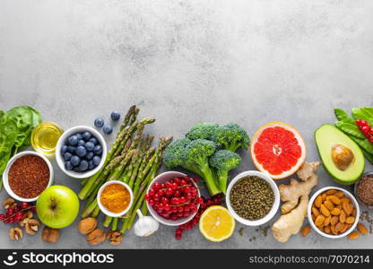 Healthy food background, spinach, quinoa, apple, blueberry, asparagus, turmeric, red currant, broccoli, mung bean, walnuts, grapefruit, ginger, avocado, almond, lemon, green peas and goji, top view