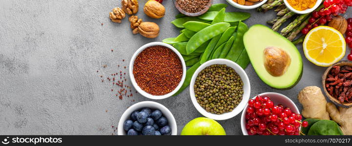 Healthy food background, spinach, quinoa, apple, blueberry, asparagus, turmeric, red currant, broccoli, mung bean, walnuts, grapefruit, ginger, avocado, almond, lemon and green peas, top view, banner