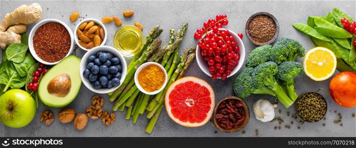 Healthy food background, spinach, quinoa, apple, blueberry, asparagus, turmeric, red currant, broccoli, mung bean, walnuts, grapefruit, ginger, avocado, almond, lemon and green peas, top view, banner