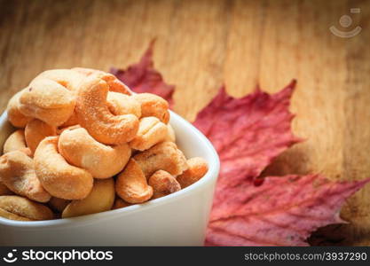 Healthy food, cashews rich in heart friendly fatty acids. Cashew nuts in white bowl on wooden old rustic table.