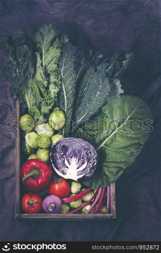 Healthy food clean eating selection in wooden box: fruit, vegetable, seeds, superfood, cereals, leaf vegetable on gray background