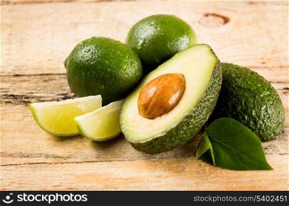 healthy food concept - avocado and lime slices on wooden background