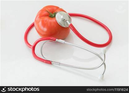 Healthy food concept - Tomato and doctor stethoscope on white backgrounds showing benefits of vitamin and nutrient in tomato.
