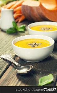 Healthy food cooking background. Vegetable ingredients and homemade soup. Fresh garden carrots, onions, pumpkins, ginger and spices on rustic wooden background. Vegetable or pumpkin soup and ingredients. Warm and comfy autumn concept.
