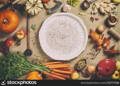 Healthy food cooking background. Vegetable ingredients. Fresh garden carrots, pumpkins, onions, apples and spices on rustic background with wooden tray in center, top view, copy space. Fresh garden carrots, pumpkins, onions, apples and spices on rustic background with wooden tray in center, top view, copy space