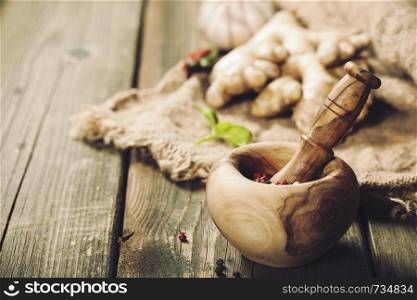 Healthy food cooking background. Wooden mortar and pestle, herbs and spices, copy space. Cooking background. Warm and comfy autumn concept.