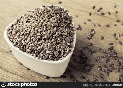 Healthy food diet. Brown flax seeds linseed in white bowl on wooden table