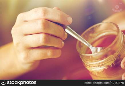 healthy food, eating and ethnoscience concept - close up of woman hands with honey and spoon. close up of woman hands with honey and spoon