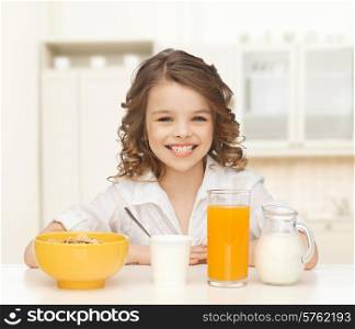 healthy food, eating, people and children concept - happy smiling beautiful girl having breakfast over home kitchen background