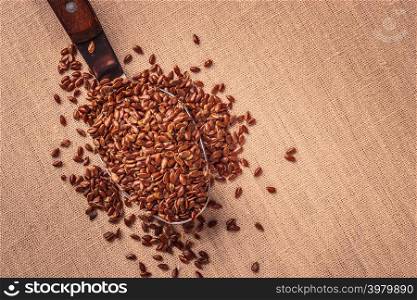 Healthy food. Flax seeds linseed on kitchen spoon burlap sack background