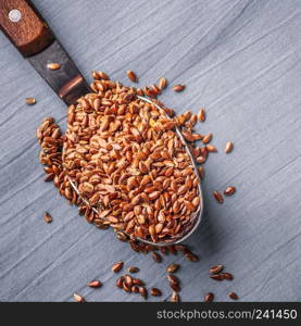Healthy food. Flax seeds linseed on kitchen spoon linen gray color background. Square format