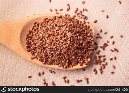 Healthy food for preventing heart diseases and overweight. Flax seeds linseed on wooden spoon burlap background