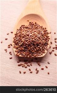 Healthy food for preventing heart diseases and overweight. Flax seeds linseed on wooden spoon burlap background