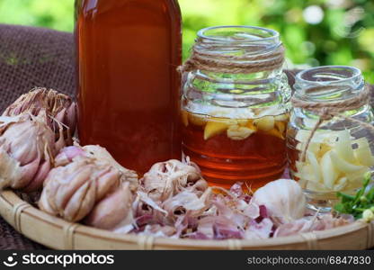 Healthy food from nature herbal, garlic soak in bee honey, a herb remedy for skin care, healthcare, three jar on green background