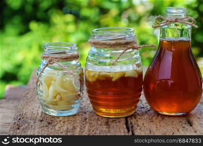 Healthy food from nature herbal, garlic soak in bee honey, a herb remedy for skin care, healthcare, three jar on green background