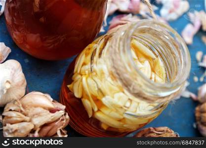 Healthy food from nature herbal, garlic soak in bee honey, a herb remedy for skin care, healthcare, three jar on blue background