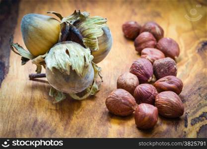 Healthy food full of fatty acids, organic nutrition. Hazelnuts kernel and cluster filbert nuts in hard shell on rustic old wooden table.