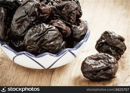 Healthy food, good cuisine. Closeup dried plums prunes fruits in bowl on wooden rustic table background