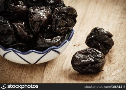 Healthy food, good cuisine. Closeup dried plums prunes fruits in bowl on wooden rustic table background