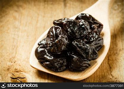 Healthy food, good cuisine. Closeup dried plums prunes fruits on wooden spoon rustic table background
