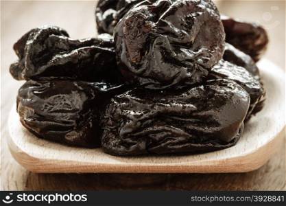 Healthy food, good cuisine. Closeup dried plums prunes fruits on wooden spoon rustic table background