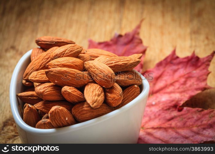 Healthy food, good for heart health. Almonds in white bowl on autumnal background