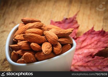 Healthy food, good for heart health. Almonds in white bowl on autumnal background