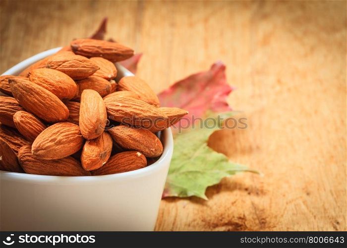Healthy food, good for heart health. Almonds in white bowl on wooden old rustic table background