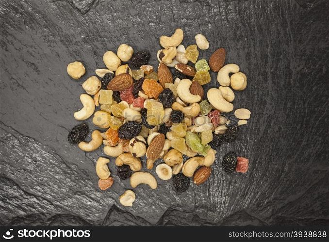 Healthy food; hazelnuts, almonds, cashew, raisin and dried fruits on a stone black background