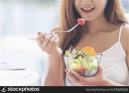 Healthy food healthy lifestyle with young happy woman eating green fresh ingredients organic salad. Vegan girl holding salad bowl with smiling face eating healthy diet food.