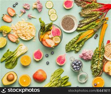 Healthy food ingredients flat lay with various fruits , vegetables, seeds and nut on light mint background. Mixer for detox drinks making, top view. Dieting and clean eating concept