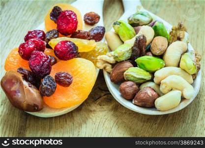 Healthy food organic nutrition. Closeup different varieties mix of dried fruits and nuts on wooden spoons.
