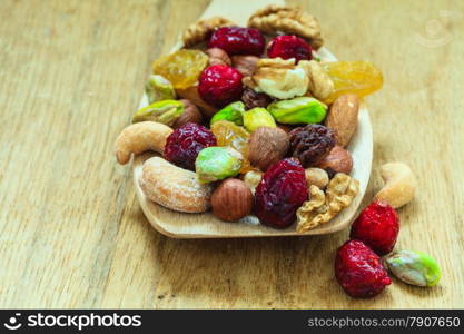 Healthy food organic nutrition. Closeup different varieties mix of dried fruits and nuts on wooden spoon.