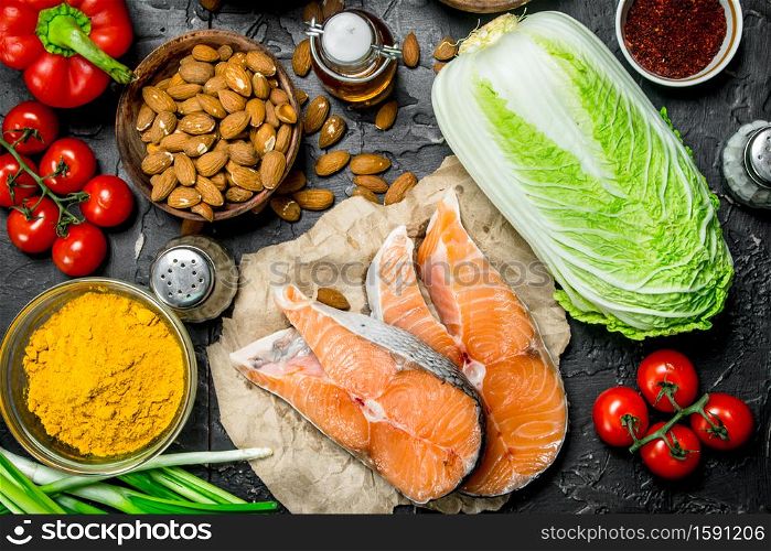 Healthy food. Salmon steaks with organic vegetable and nuts. On a black rustic background.. Healthy food. Salmon steaks with organic vegetable and nuts.