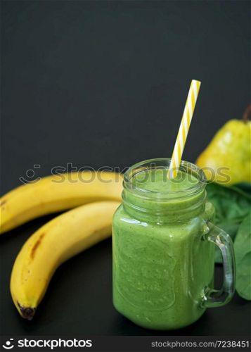 Healthy food. Smoothies and ingredients for detox, banana, pear, spinach leaves on a black background, top view, copy space.