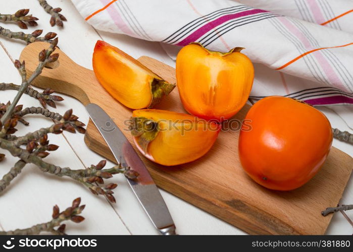 healthy food. Two persimmons are on the board, a knife and a towel