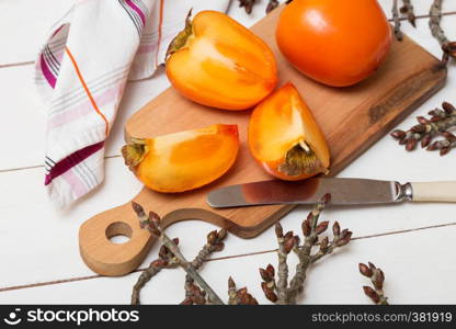 healthy food. Two persimmons are on the board, a knife and a towel