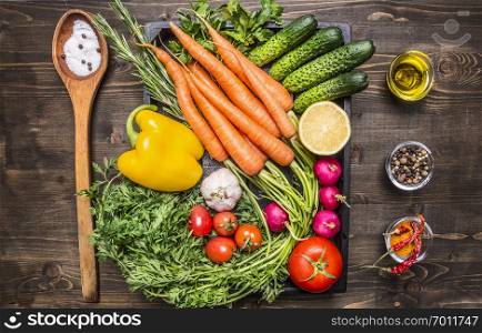 Healthy foods, cooking and vegetarian concept fresh carrots cherry tomatoes, garlic, cucumber, lemon, pepper, radish, wooden spoon salt pepper colored, oil wooden rustic background top view close up
