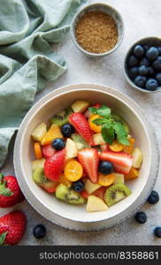 Healthy fresh fruit salad in a bowl on concrete background