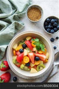 Healthy fresh fruit salad in a bowl on concrete background
