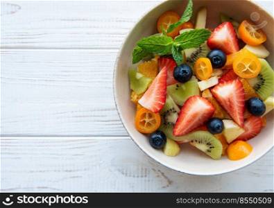 Healthy fresh fruit salad in a bowl on wooden background