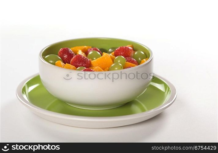 Healthy fresh fruit salad out of mango, strawberry and white grapes in green-white bowl photographed on white (Selective Focus, Focus on the middle) . Fresh Fruit Salad