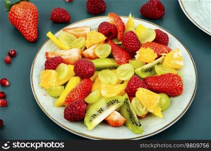 Healthy fresh fruit with mango, juicy citrus, banana and berries in a bowl. Fruit salad of citrus and berries