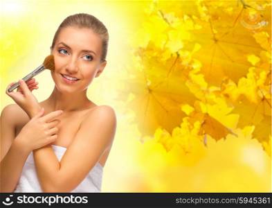Healthy girl with makeup brush on autumn background