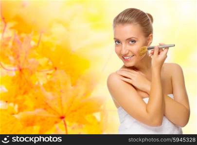 Healthy girl with makeup brush on autumnal background