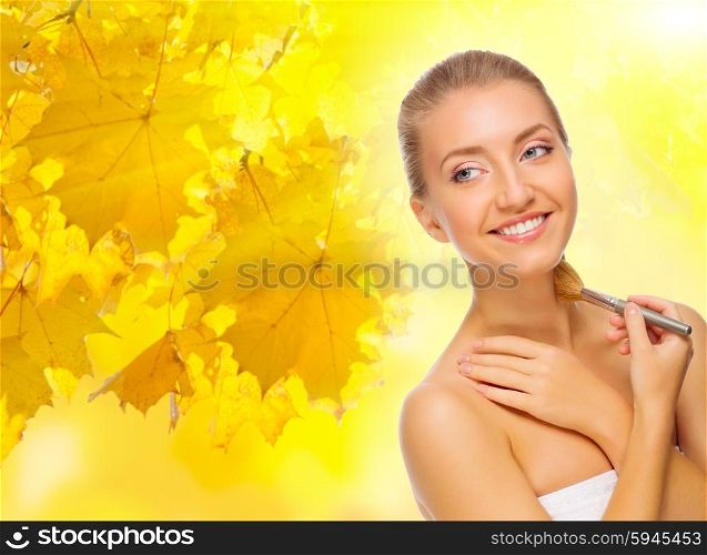Healthy girl with makeup brush on autumnal background